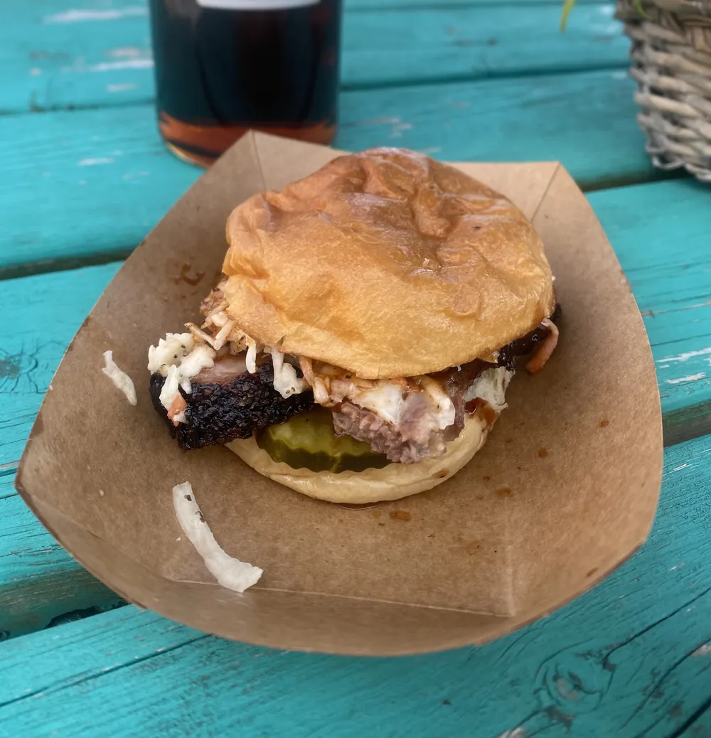 A brisket sandwich on a teal picnic table