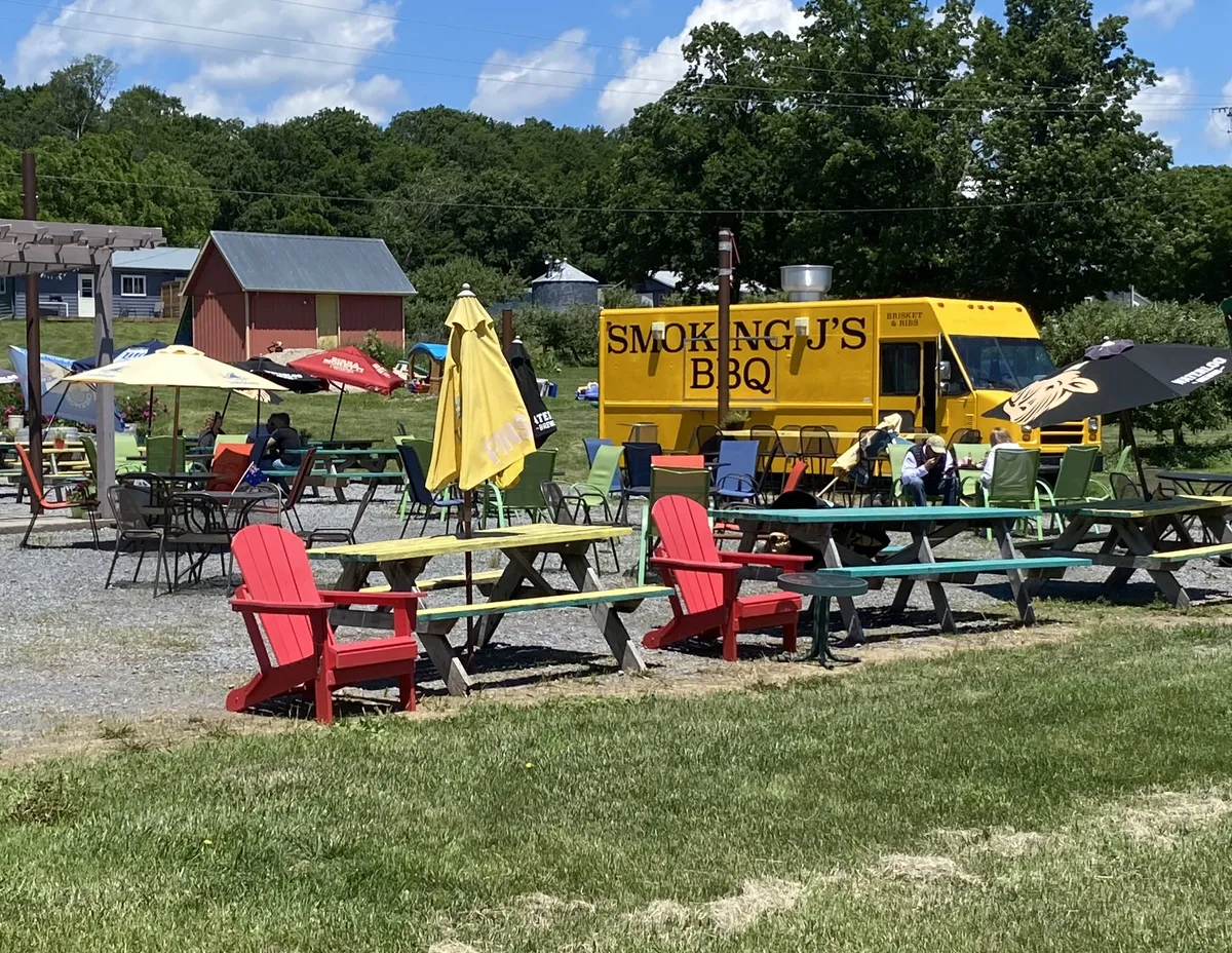Picnic tables and red Adirondack chairs on the lawn by the truck