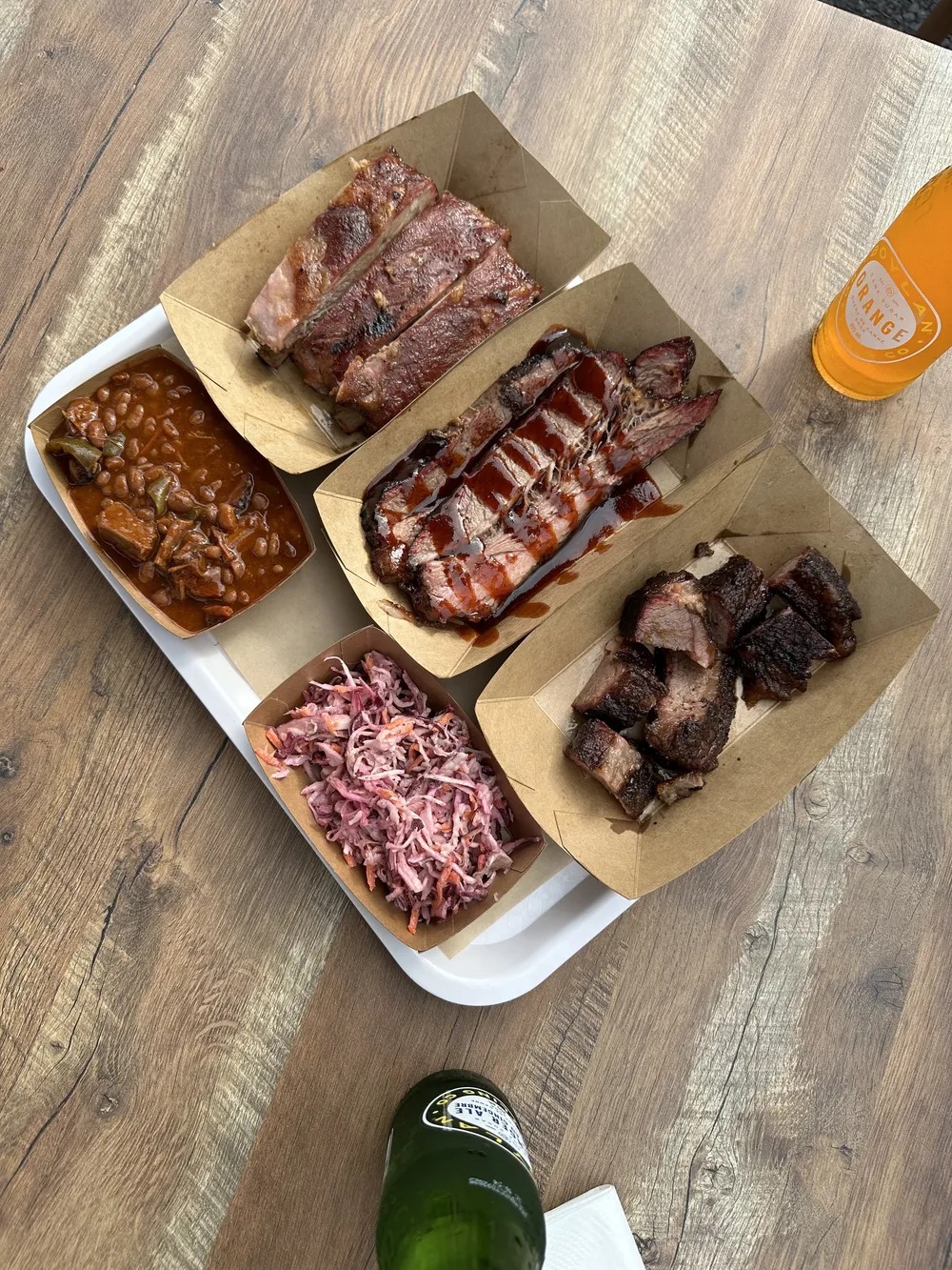 A tray of sliced brisket, pork ribs, burnt ends and coleslaw