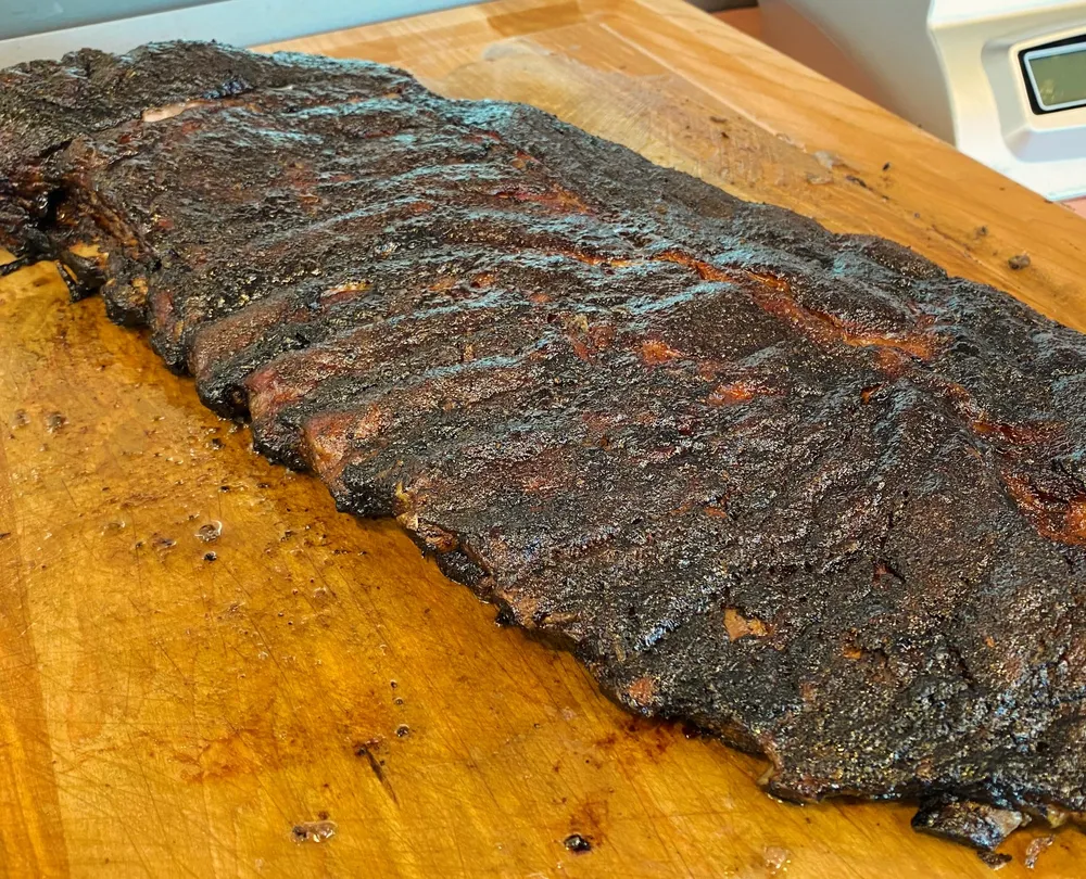 A rack of smoked pork ribs on a cutting board