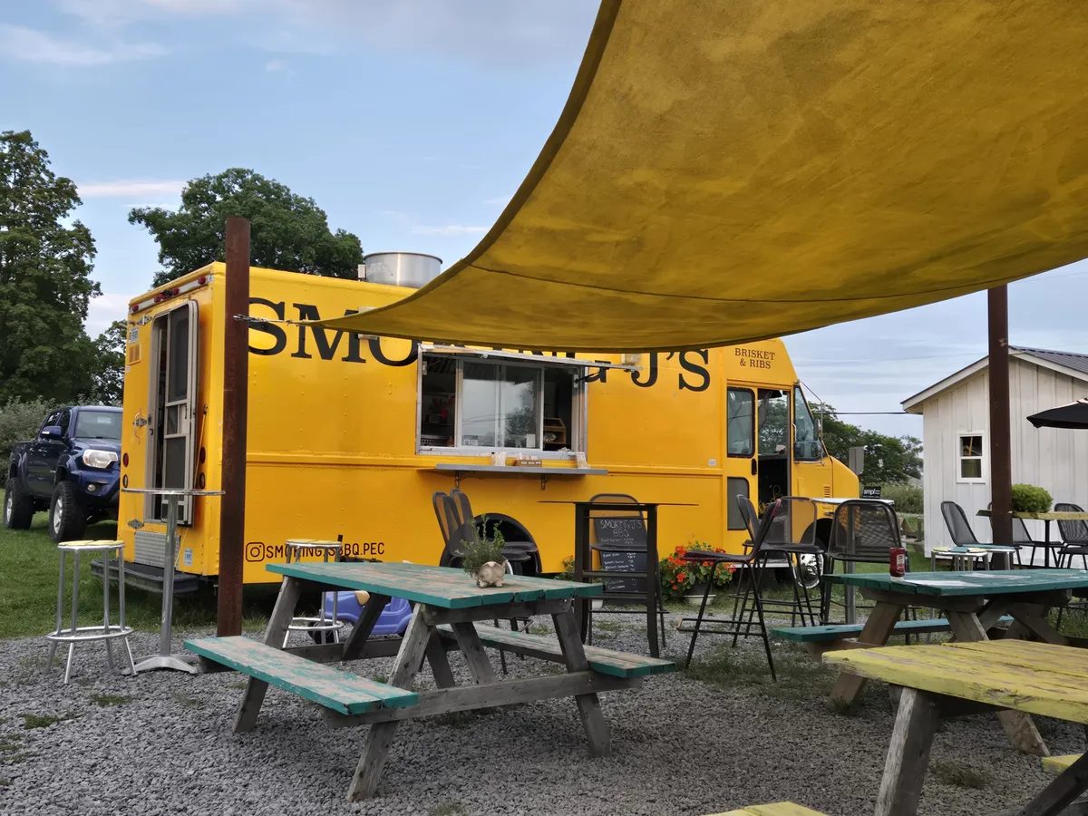 The yellow truck with picnic tables and a shade sail on the lawn